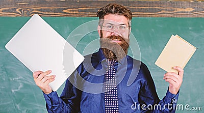 Digital against paper. Teacher bearded hipster holds book and laptop. What would you prefer. Teacher choosing modern Stock Photo