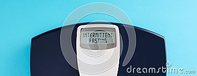 Digital bathroom scale with the word intermittent fasting on blue background Stock Photo