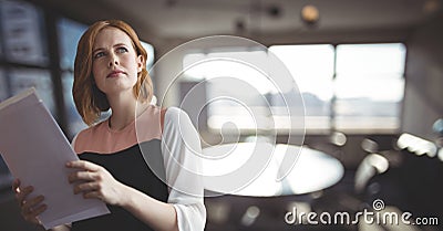 Confused business woman holding files against office background Stock Photo