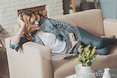 Pleasant young woman reading electronic book Stock Photo