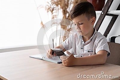 digital generation child doing homework using a mobile phone. Lessons with a gadget via the Internet. A schoolboy writes Stock Photo