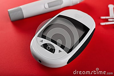Digital glucometer, lancets and pen on red background. Diabetes control Stock Photo