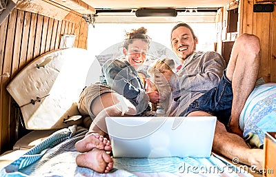 Digital nomad couple with cute dog using laptop on retro mini van transport - Travel life inspiration concept with indie people Stock Photo