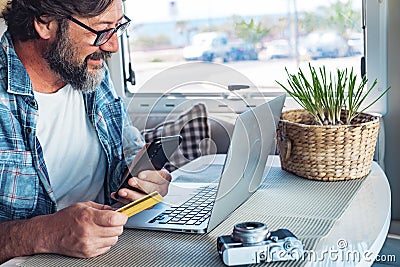 Digital nomad and remote worker freedom lifestyle concept. Adult man buying on line using laptop and mobile phone connection Stock Photo