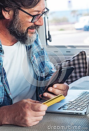 Digital nomad and remote worker freedom lifestyle concept. Adult man buying on line using laptop and mobile phone connection Stock Photo