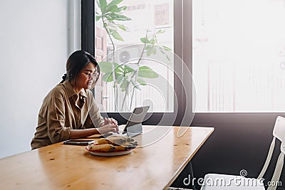 Digital nomad woman working online on the table of hostel while going abroad. Stock Photo