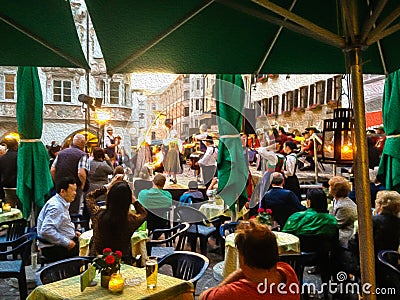 Digital Oil Painting of audience at outdoor restaurant watching Traditional Performance in Old Town Innsbruck, Tirol, Austria Stock Photo