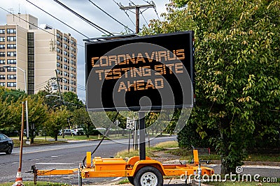 Digital road sign by a suburban street that says Coronavirus Testing Site Ahead. Stock Photo