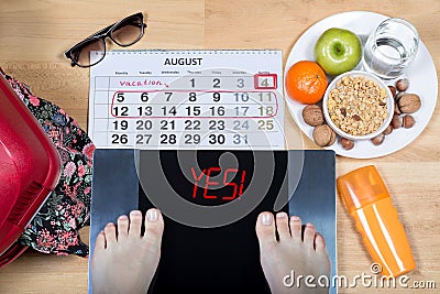 Digital scales with female feet sign `yes!` surrounded by calendar, summer accessories and plate with healthy food. Stock Photo