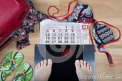 Digital scales with female feet on them and sign`no!` surrounded by calendar and summer holiday accessories. Stock Photo