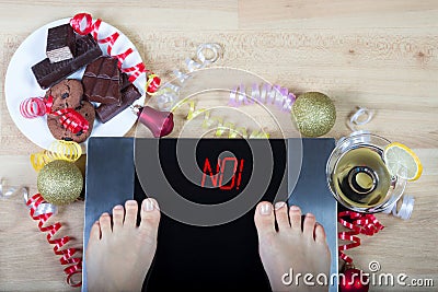 Digital scales with female feet on them and sign `no!` surrounded by christmas decorations and unhealthy food. Stock Photo