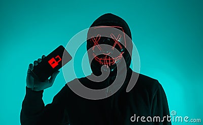 Digital security Concept. Anonymous hacker with mask holding smartphone hacked Stock Photo