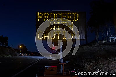 Digital sign at a freeway onramp stating Proceed With Caution Stock Photo