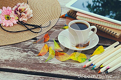 Digital tablet, books, colorfull pencils and cup of coffee on old wooden table outdoor in the park Stock Photo
