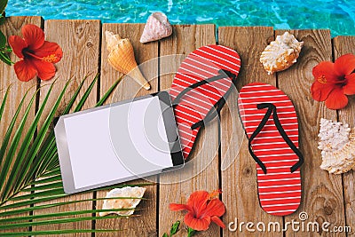 Digital tablet, flip flops and hibiscus flowers on wooden background. Summer holiday vacation concept. View from above Stock Photo