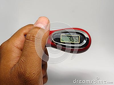 Digital tasbih counter held in hand, showing a close-up of a red and silver device with an LCD screen for counting. Stock Photo