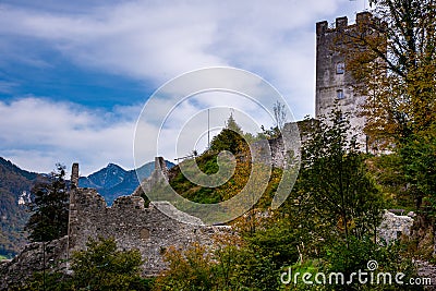 A dilapidated ruin of an old knight's castle, overgrown with green trees and bushes, and damaged - taken on a cloudy summer Stock Photo