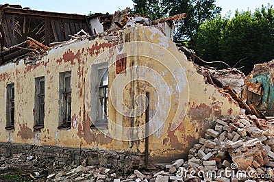 A dilapidated white brick building with a broken wooden roof Stock Photo