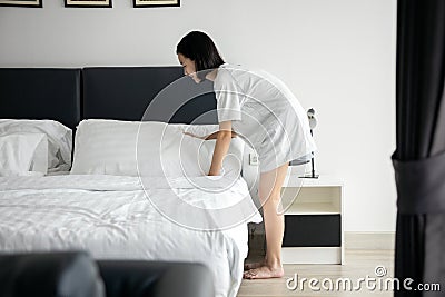 Diligent child daughter making bed and bedding in her parent`s bedroom,help with housekeeping at home,asian girl cover the bed Stock Photo