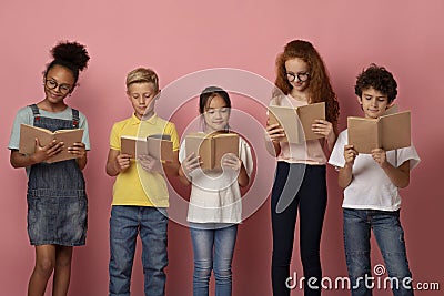 Diligent pupils of different races reading books together over pink background Stock Photo