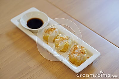 Dim Sum Recipe - Chinese shrimp dumplings topped with fried garlic, served with sour sauce. Stock Photo