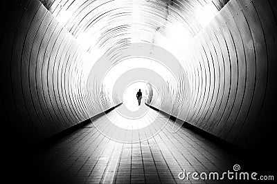 Diminishing perspective of unrecognizable man in a bright public tunnel Stock Photo