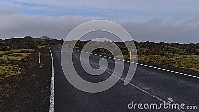 Winding country road with markings between moss covered lava fields of volcanic stones near Grindavik, Reykjanes, Iceland. Stock Photo