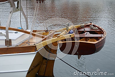 Dinghy, small rowing boat made of mahogany wood, attached to the stern of a sailing yacht Stock Photo