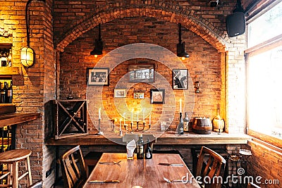 Dining table of Italian restaurant decorated with brick and photo frames in warm light that created cozy atmosphere Editorial Stock Photo