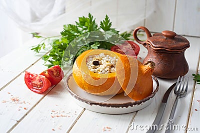 Dinner dish: pumpkin stuffed with pearl barley with vegetables on a white plate on a white background. Close-up. Stock Photo