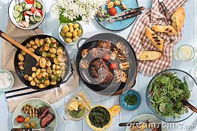 Dinner table with grilled steak, vegetables, potatoes, salad, sn Stock Photo
