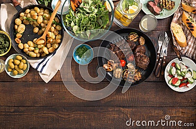 Dinner table with grilled steak, vegetables, potatoes, salad, sn Stock Photo