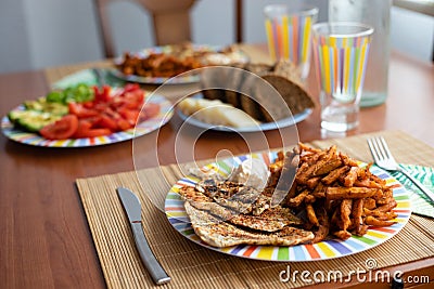Dinner table with salad dish, chicken, sweet potatoes, bread and colorful water glass Stock Photo