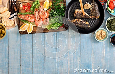 Dinner table with shrimp, fish grilled, salad, snacks with border Stock Photo