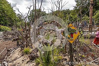 Dinosaurs fighting for some food, in the foreground a yellow that says you must not feed the dinosaurs Editorial Stock Photo