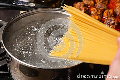 Dip spaghetti into boiling water in a saucepan. Pasta cooking Stock Photo