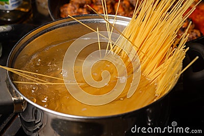 Dip spaghetti into boiling water in a saucepan. Pasta cooking Stock Photo