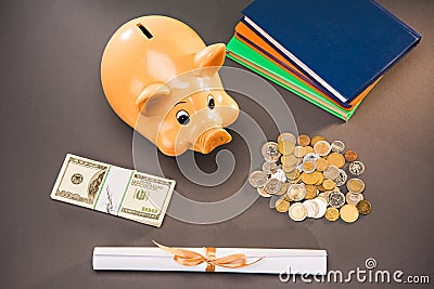 Diploma, books and piggy bank with coins and dollars on grey Stock Photo