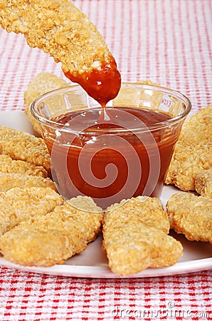 Dipping chicken finger in BBQ sauce Stock Photo