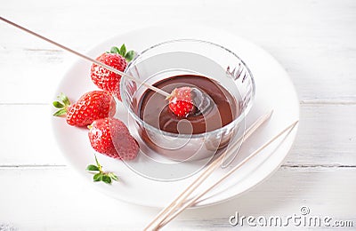 Dipping strawberry in chocolate cream on white wood Stock Photo