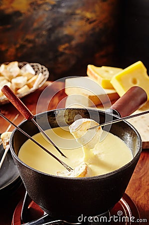Dipping into a tasty cheese fondue with bread Stock Photo