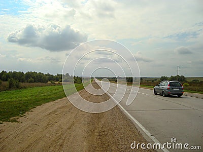 Direct asphalt road through the countryside under the sky, on which the clouds float Stock Photo