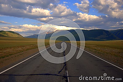 A direct asphalt road going beyond the horizon rests on mountain ranges. Kurai steppe, Altai, Russia. Landscape Stock Photo