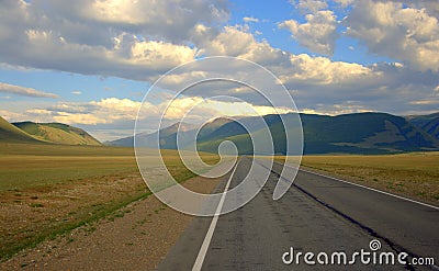 A direct asphalt road running through the valley rests on the mountains Stock Photo