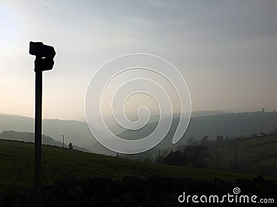 Direction sign in silhouette over misty landscape at daybreak with mist covered hills and valley just before sunrise Stock Photo