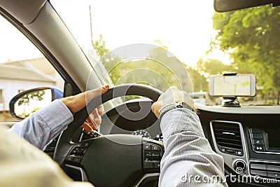 Car interior with male driver sitting behind the wheel, soft sunset light. Luxurious vehicle dashboard and electronics. Stock Photo