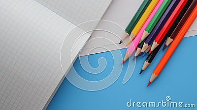 Directly Above Shot Of Colored Pencils By Books On blue background Stock Photo