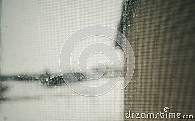 Focus on a dirty residential windo overlooking the side of a house and snow covered area Stock Photo