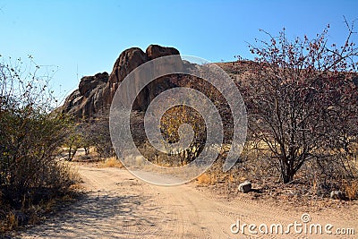 A dirt road along a picturesque rocky canyon in perspective under a blue sky Stock Photo