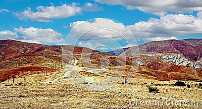 Dirt road through dry arid barren desert valley with colorful mountain range - Cordillera Copiapo, Chile Stock Photo
